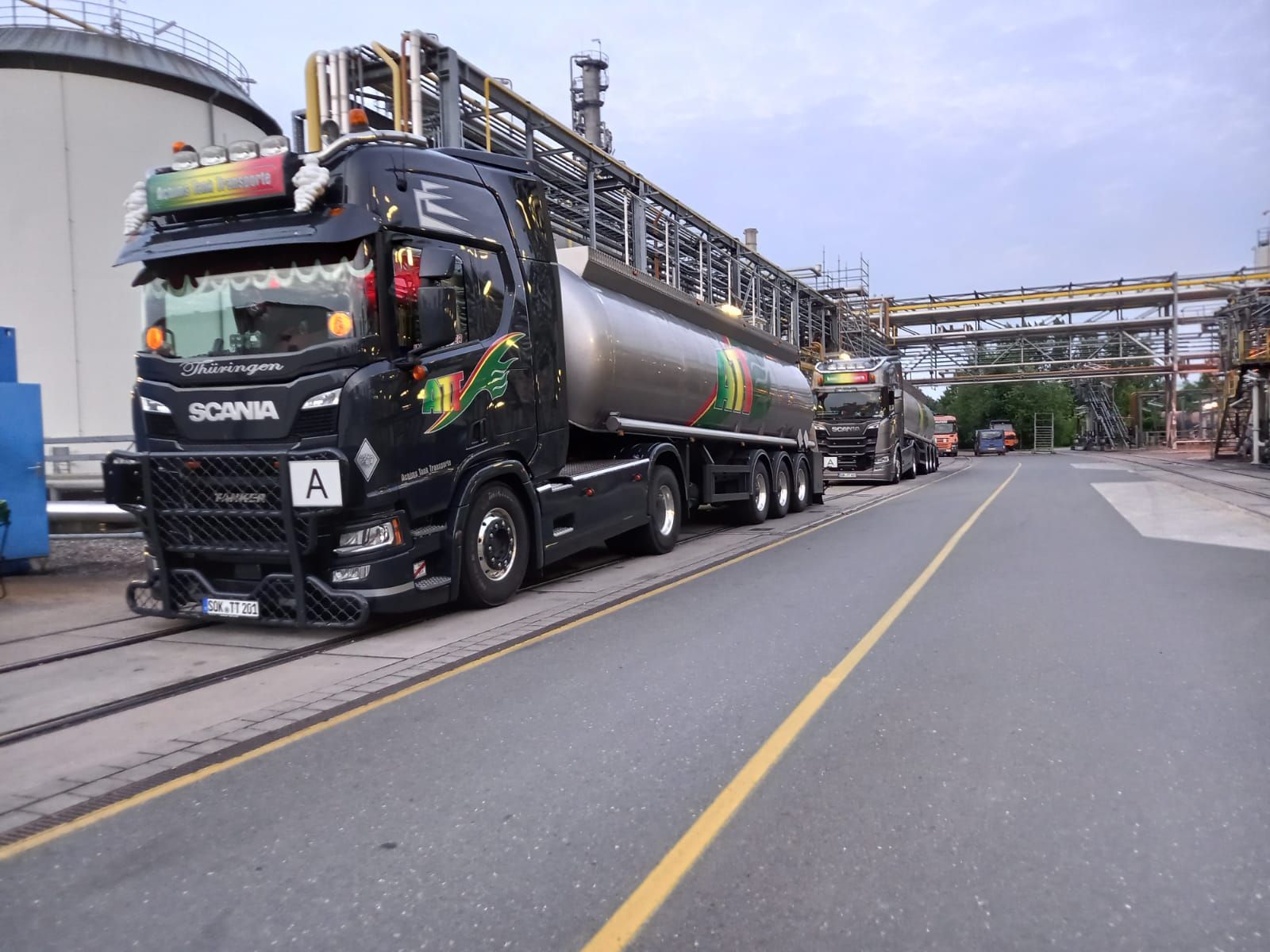 Schwarzer Tankwagen mit silbernem Tank, der auf einer Industriestraße geparkt ist.