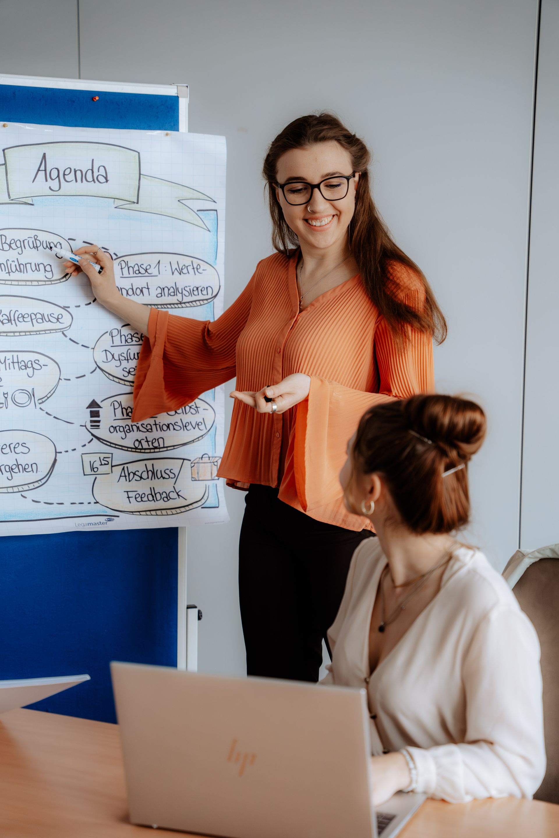 Zwei Frauen stehen nebeneinander vor einem Whiteboard.