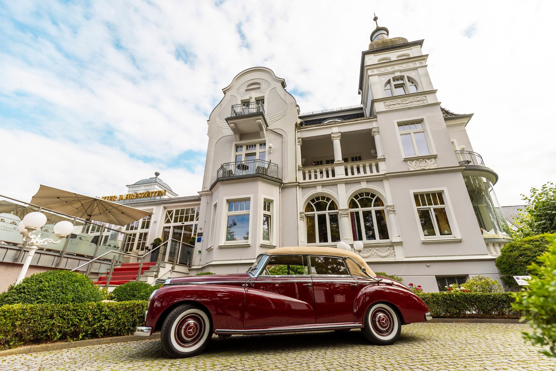 Ein rotes Auto parkt vor einem großen weißen Gebäude.