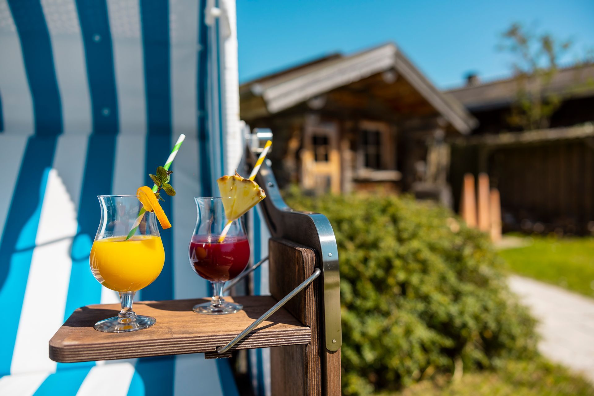 Zwei bunte Cocktails auf einem Holztablett.