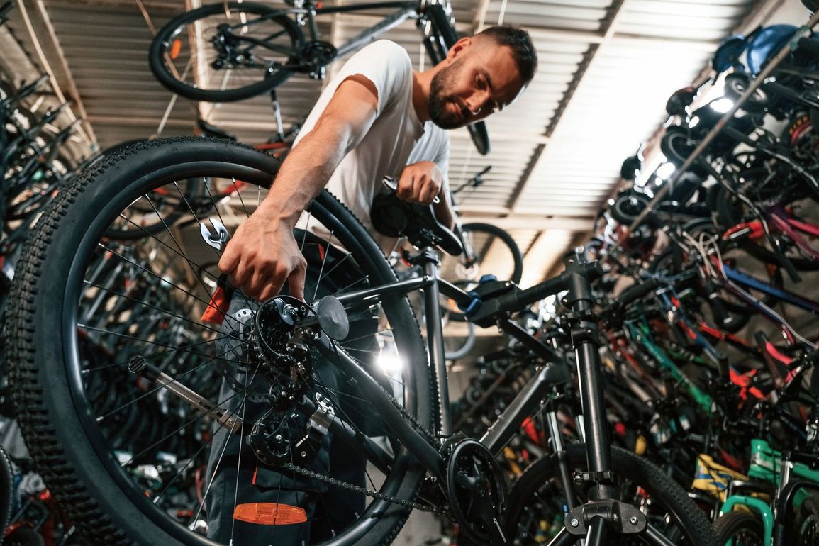 Mécanicien travaillant sur un vélo suspendu dans un atelier spécialisé