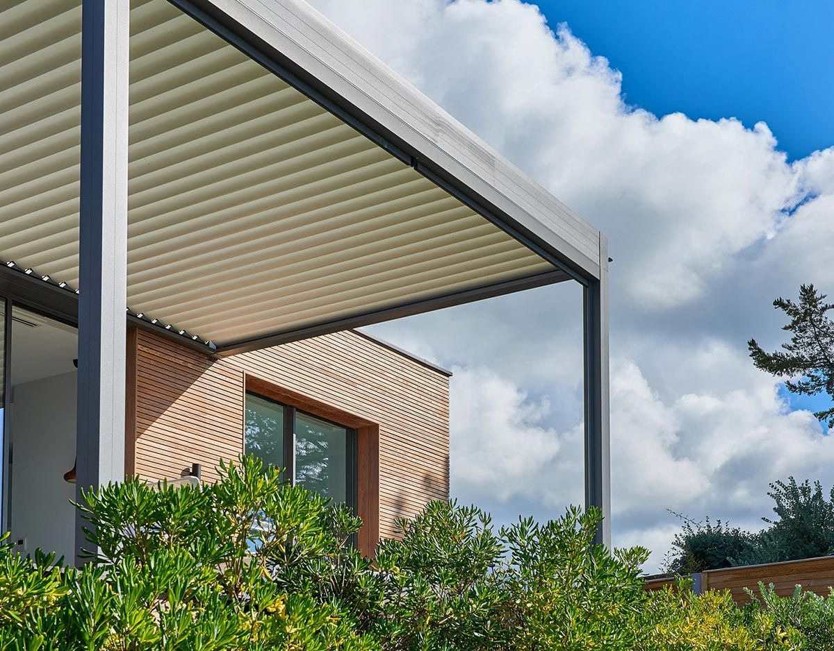 Pergola bioclimatique à côté d'une haie
