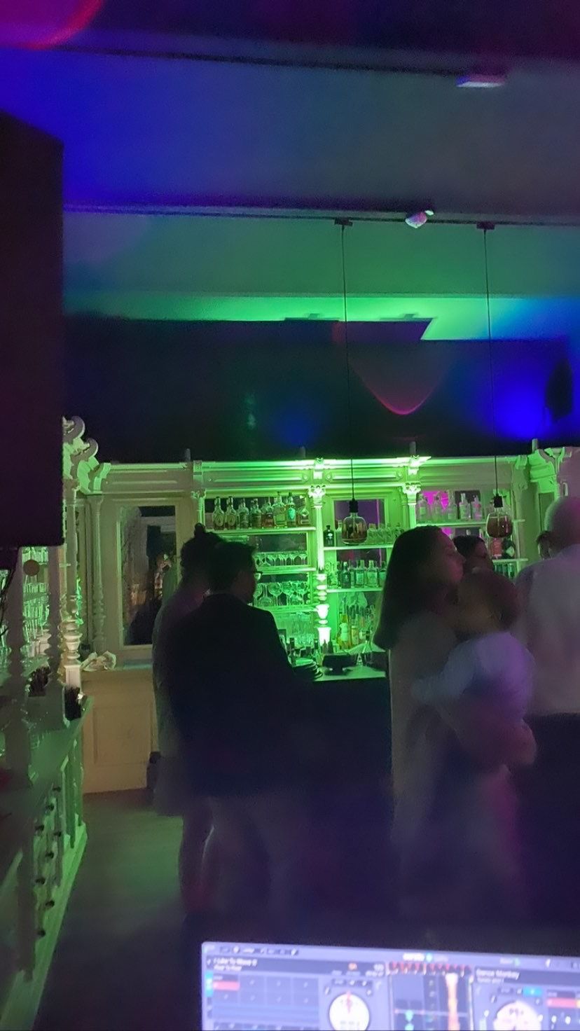 Eine Gruppe von Leuten steht in einem dunklen Raum um eine Bar herum.