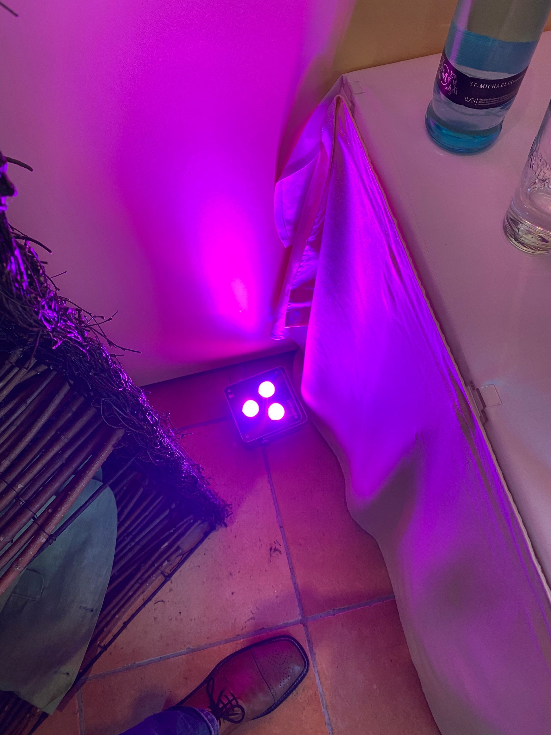 Eine Person steht neben einem Tisch mit violetten Lichtern darauf.