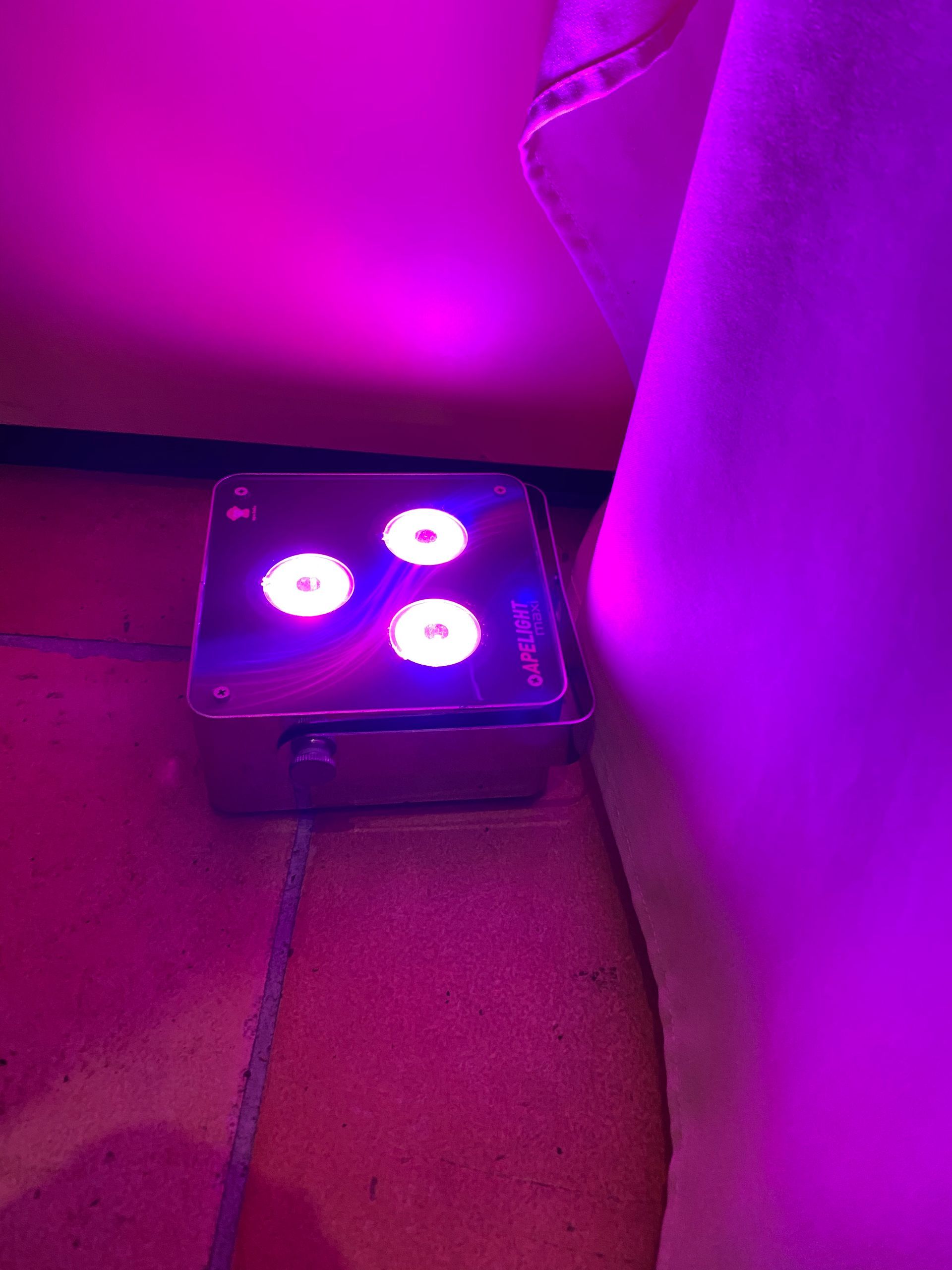 Auf dem Boden neben einem Sofa steht ein violettes Licht.