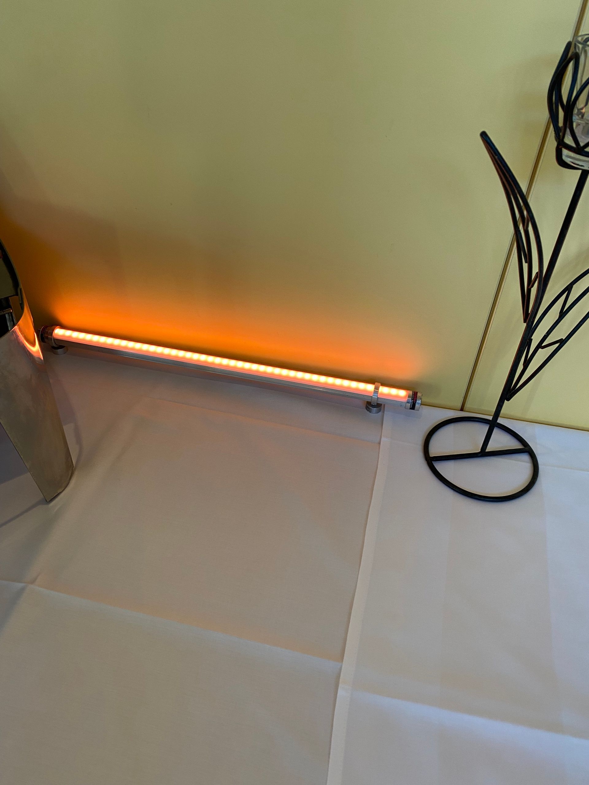 Ein Kerzenhalter auf einem Tisch mit einer gelben Wand im Hintergrund