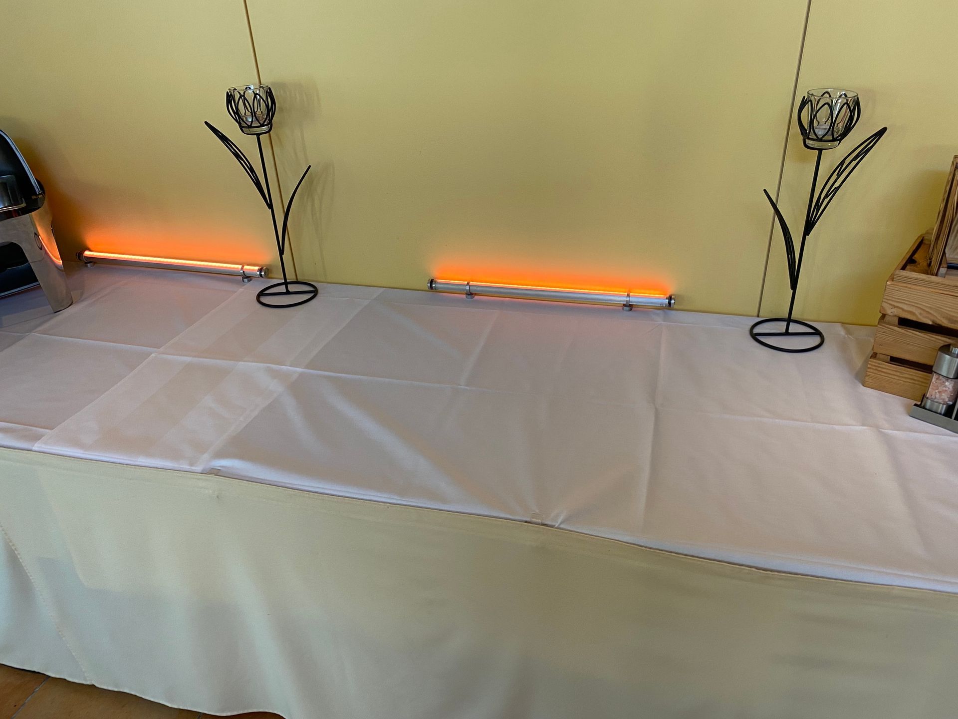 Ein Tisch mit einer weißen Tischdecke und zwei Kerzen darauf