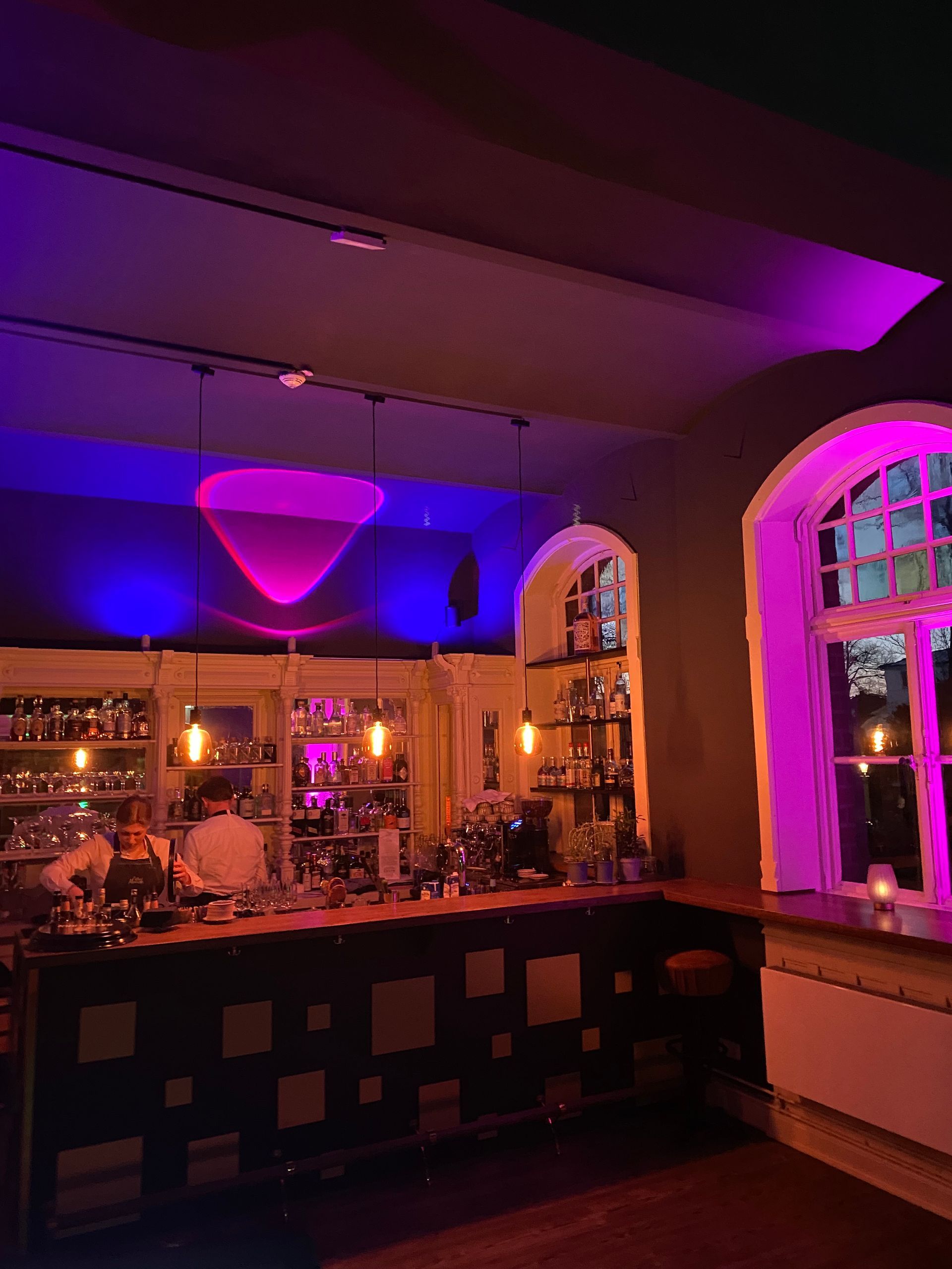 Eine Bar mit violetten Lichtern an der Decke und einem Fenster.