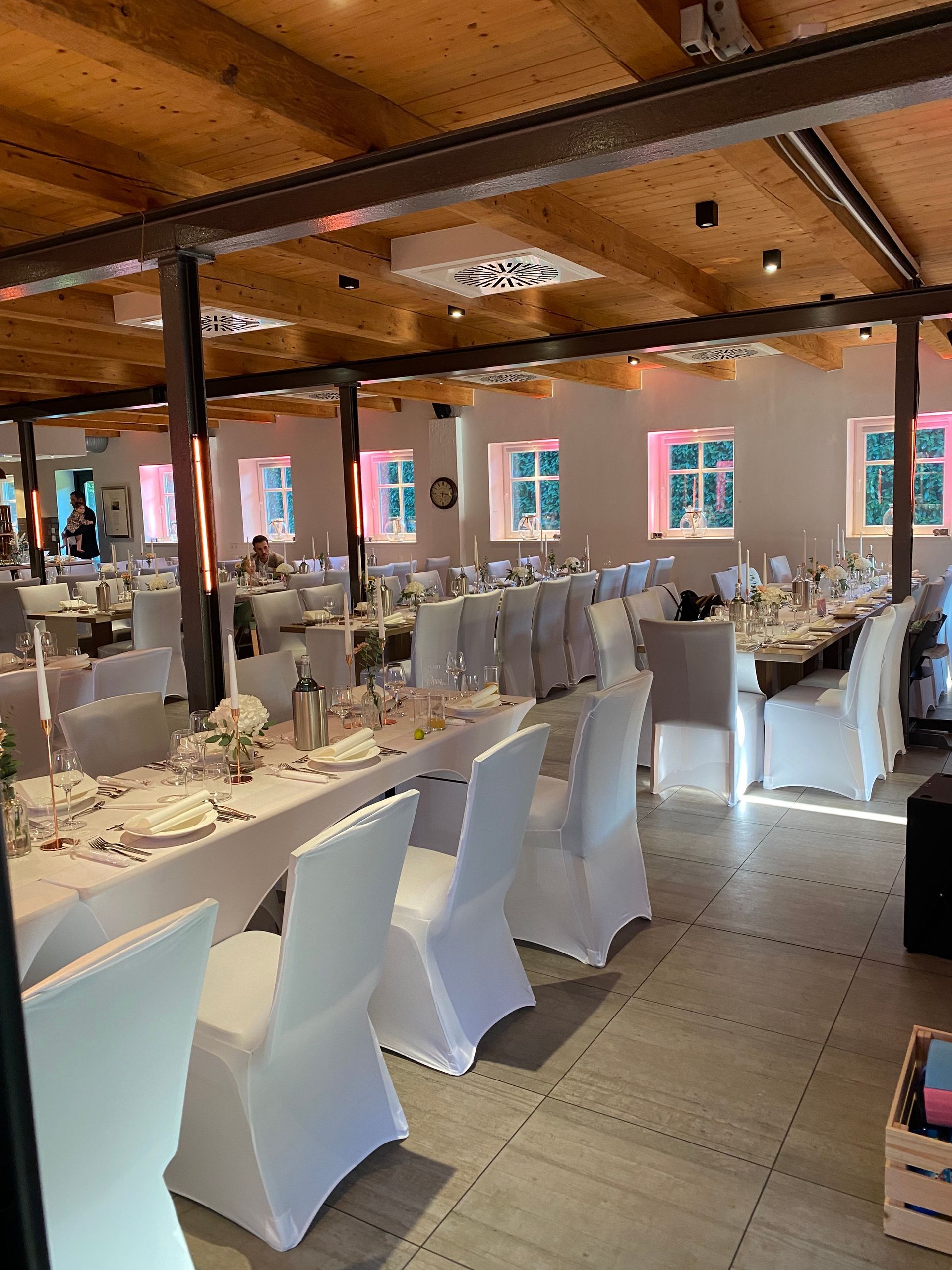 Ein großer Raum mit Tischen und Stühlen, aufgestellt für einen Hochzeitsempfang.