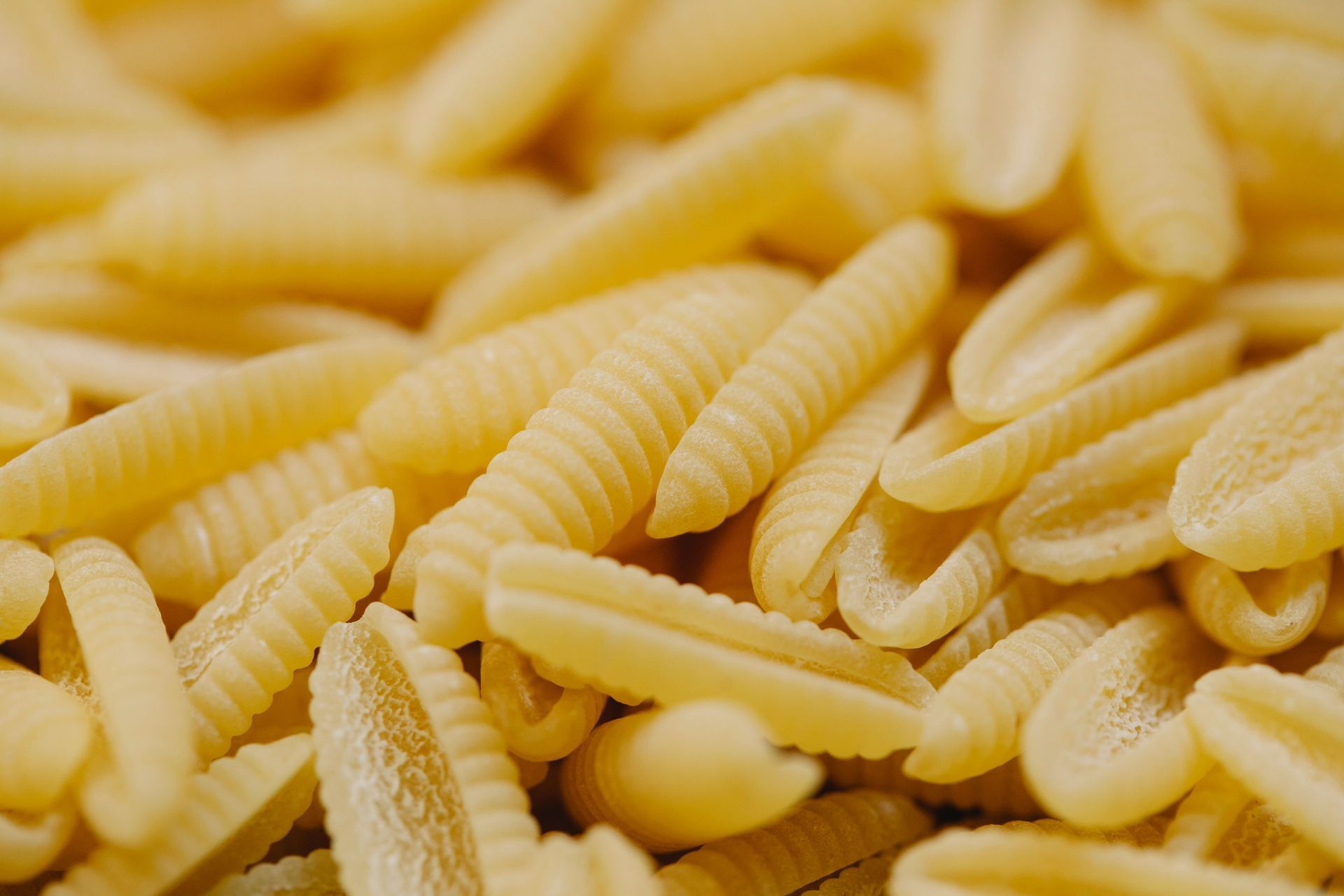 Ein Teller Spaghetti mit Kräutern und Käse, serviert in einem Restaurant mit Weingläsern im Hintergrund.
