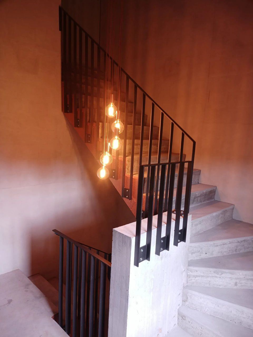 Treppenhaus mit schwarzem Geländer und brennenden Kerzen auf dem Treppengeländer neben einer weissen Treppe.