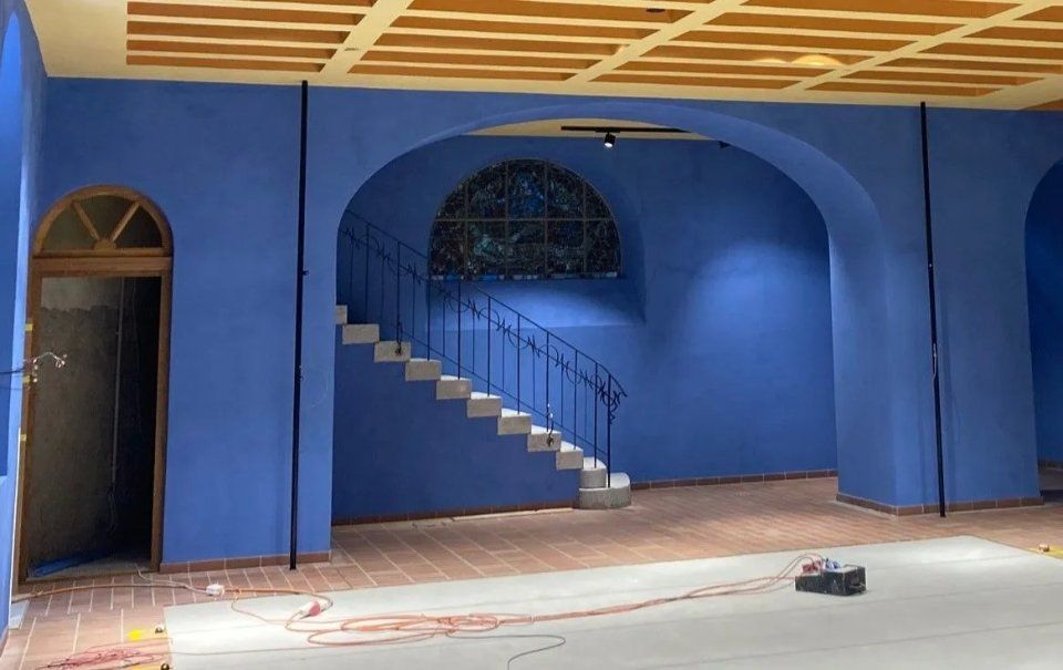 Blauer Innenraum mit Bogenfenstern, Treppenhaus und im Bau befindlicher, freiliegender Holzdecke