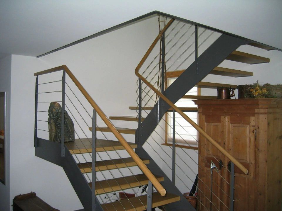 Moderne Innentreppe mit grauen Stufen, Metallgeländer und Holzhandläufen in einem weissen Raum