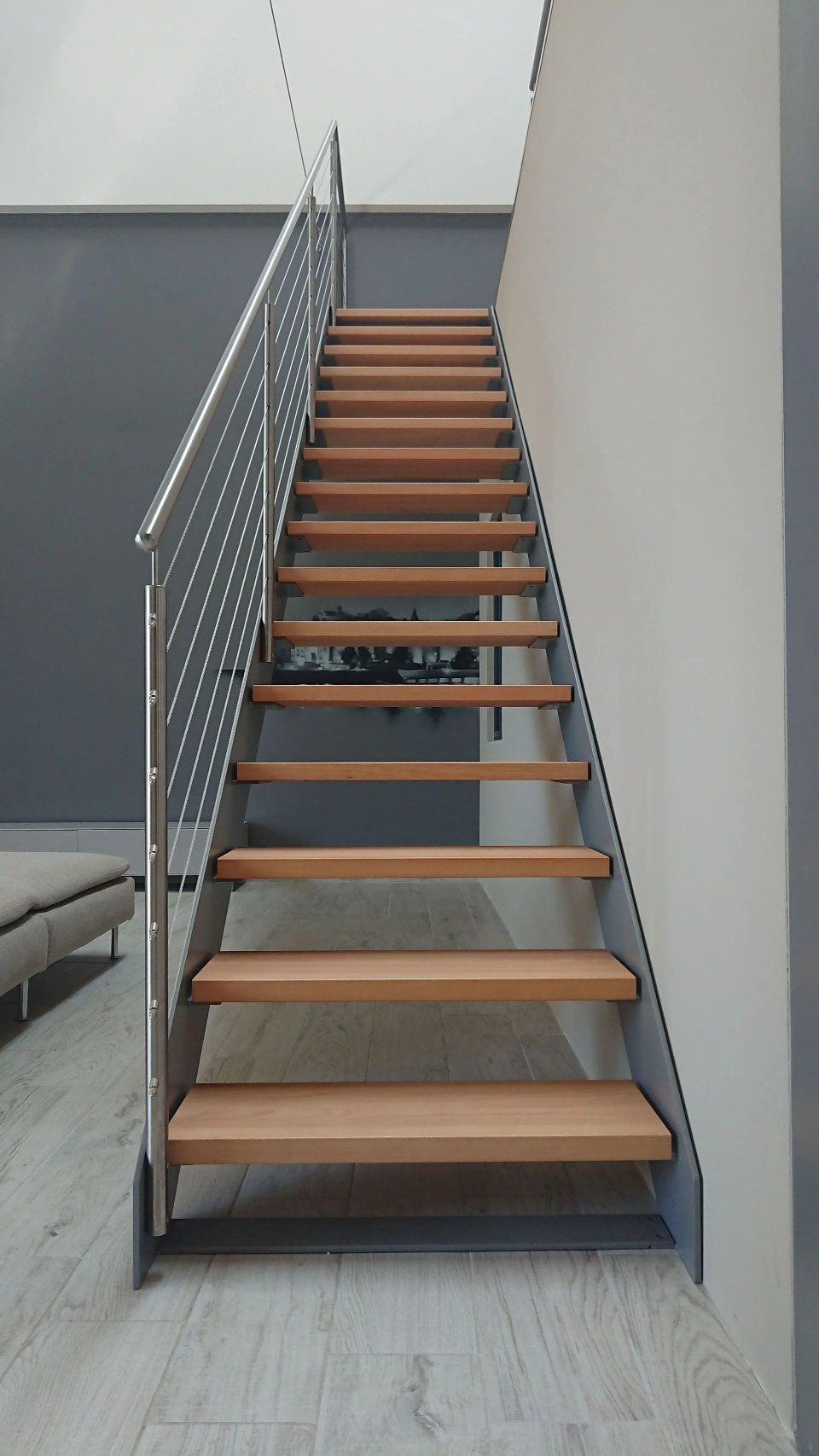 Innentreppe mit Holzstufen, Metallgeländer und grauen Wänden in einem modernen Flur