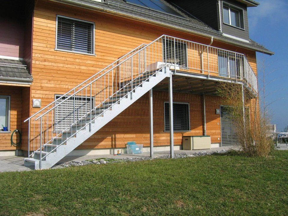 Aussenansicht eines Backsteinhauses mit langer Metalltreppe und Rasenfläche