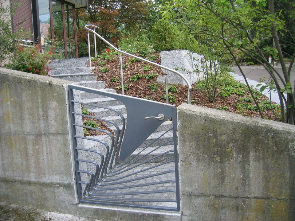 Metalltor in der Betonmauer neben der Aussentreppe und dem Gartenweg