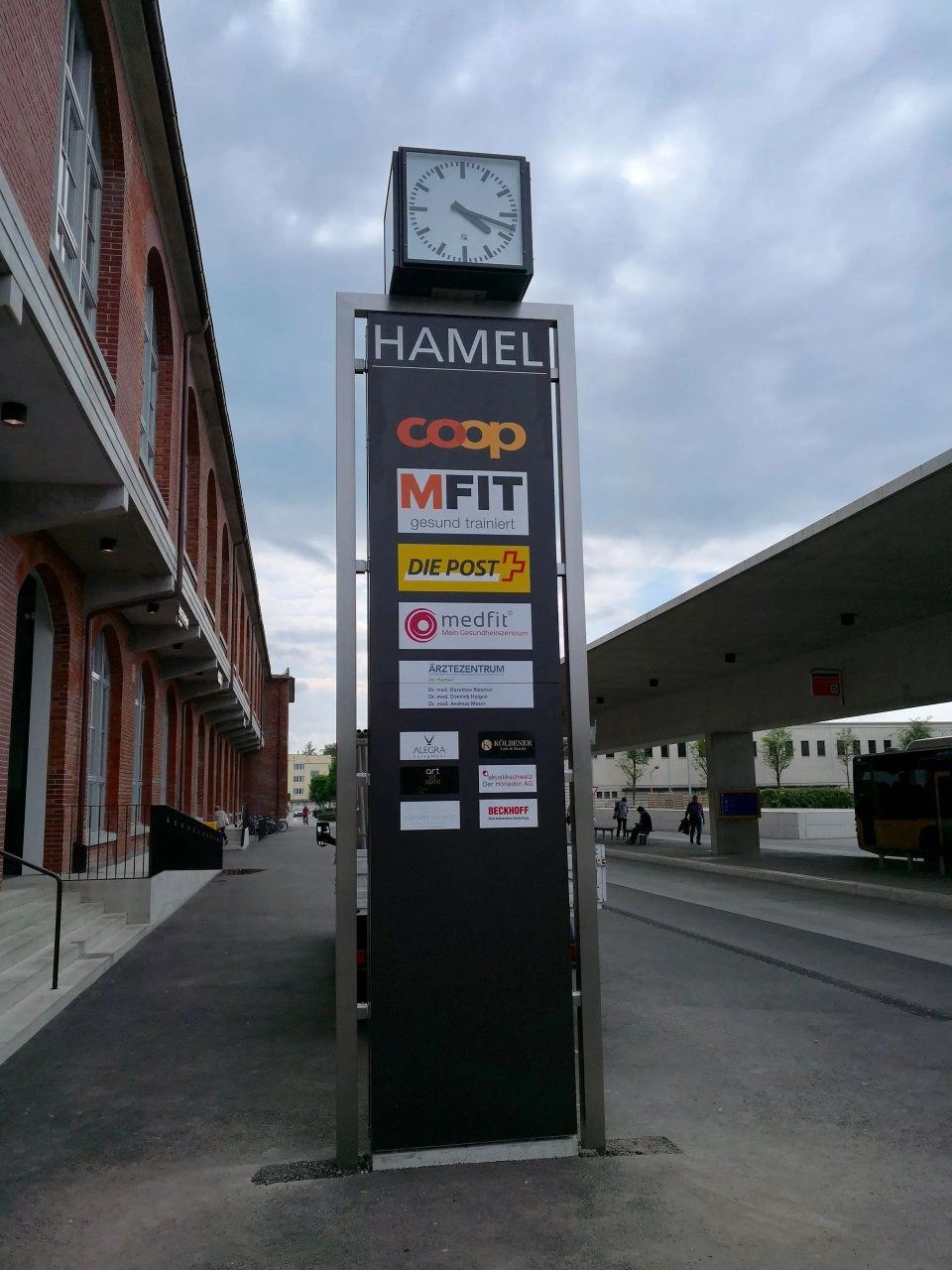 Ein Hamel-Werbeturm steht an einer Strasse in der Stadt, obenauf befindet sich eine Uhr und darunter die Logos der Sponsoren.