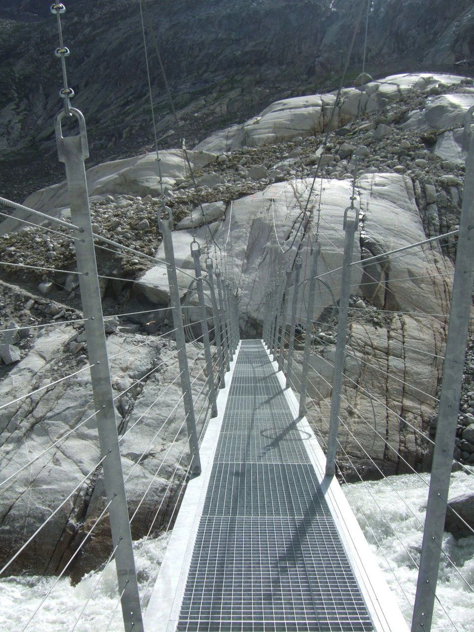 Schmale Metallhängebrücke über felsiges Gelände in einem Gebirge