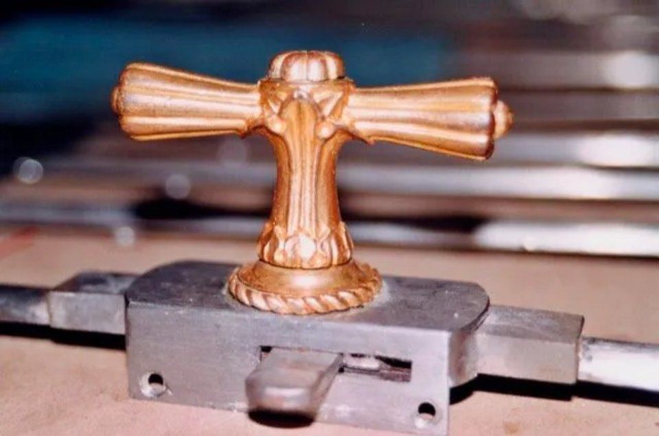 Kleine goldene Trophäenfigur auf einem grauen Sockel, zentriert auf einer Metalloberfläche mit verschwommenem Hintergrund