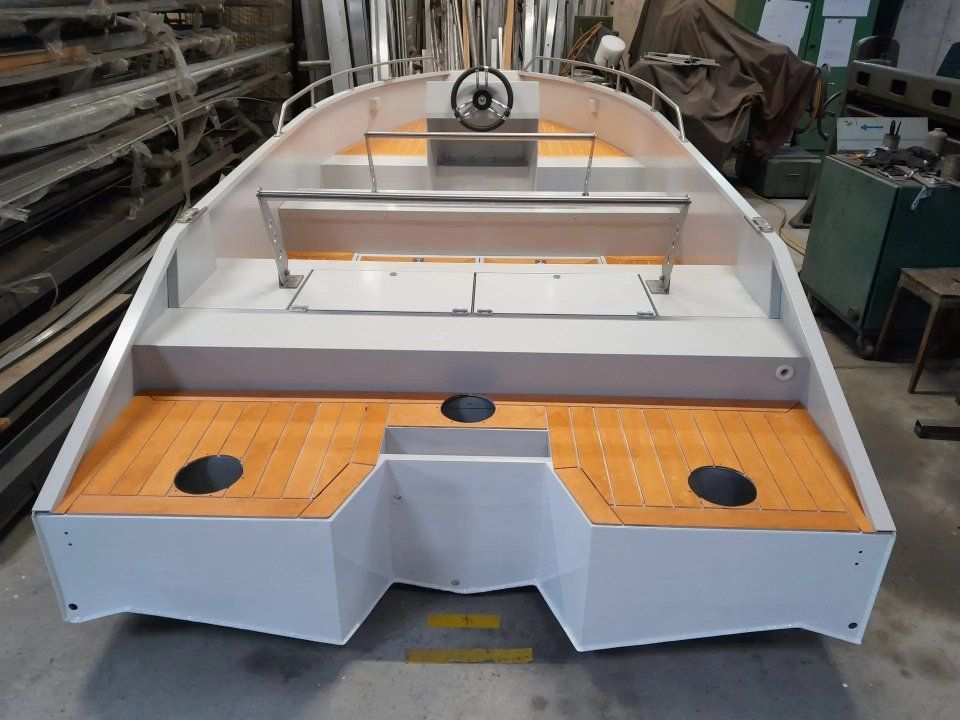 Grosser weisser Bootsrumpf mit orangefarbenen Deckplatten im Bau in einer Werkstatt
