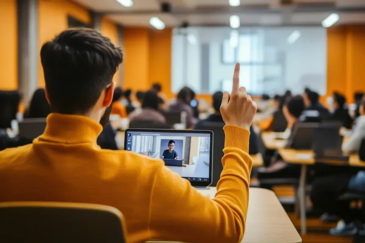 Estudiante con cuello alto amarillo levanta la mano, viendo una clase en un ordenador portátil en un aula.