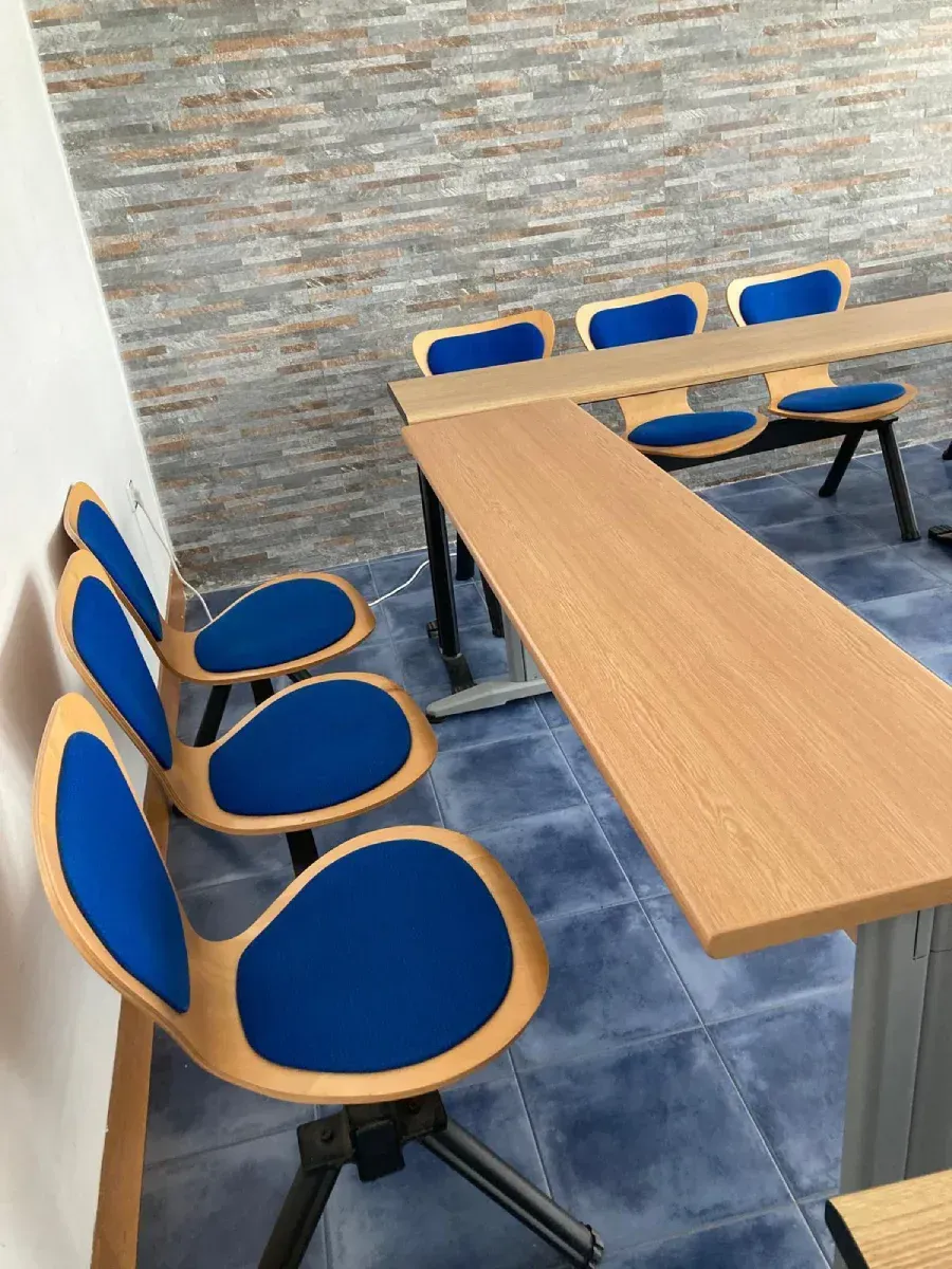 Sillas azules con estructura de madera dispuestas alrededor de una larga mesa de madera