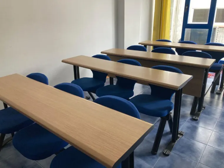 Aula con filas de pupitres y sillas azules.