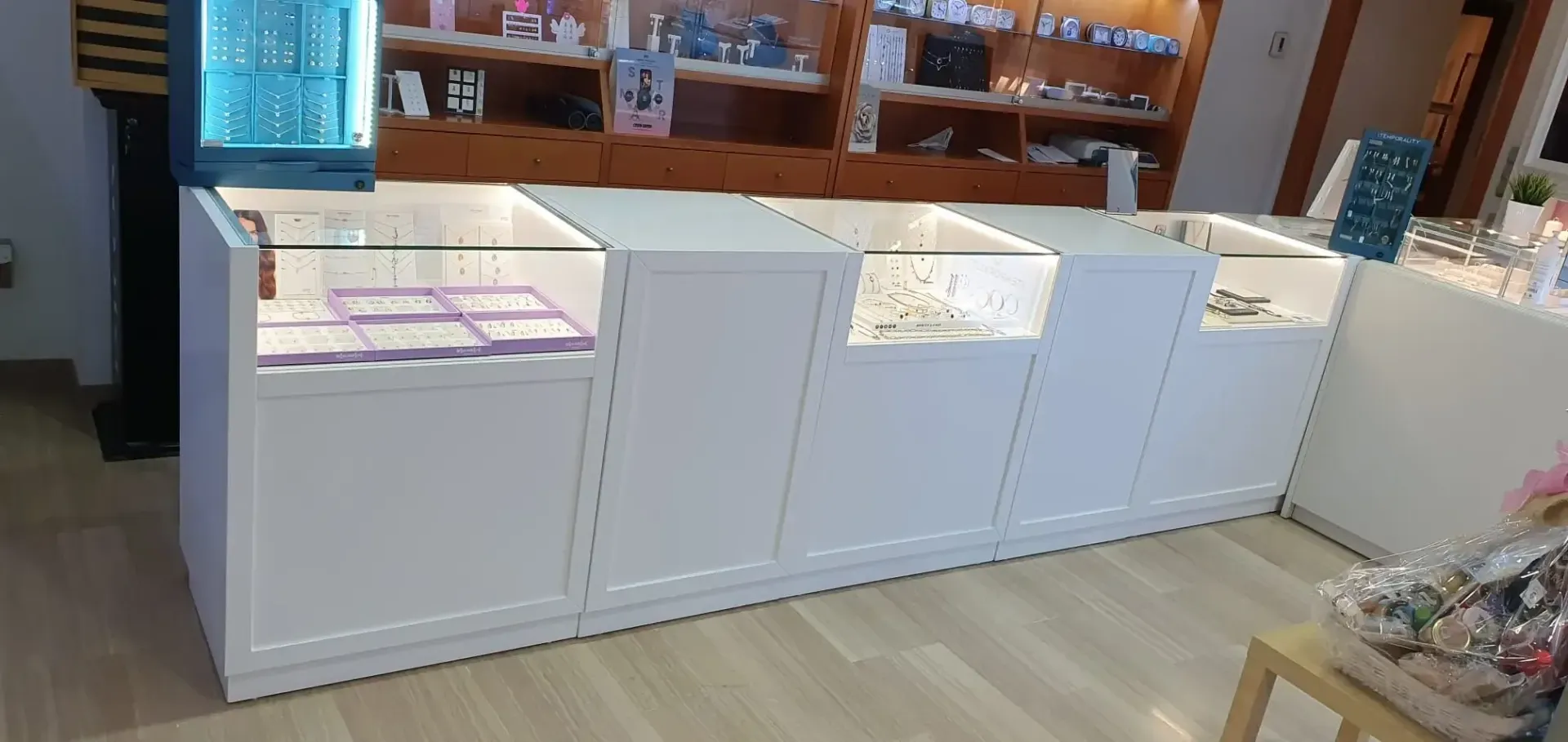 Una fila de vitrinas blancas llenas de joyas en una tienda.