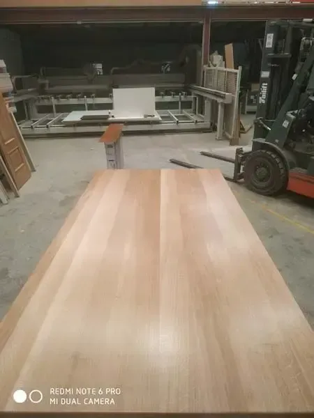 Una mesa de madera está colocada en un almacén al lado de una carretilla elevadora.