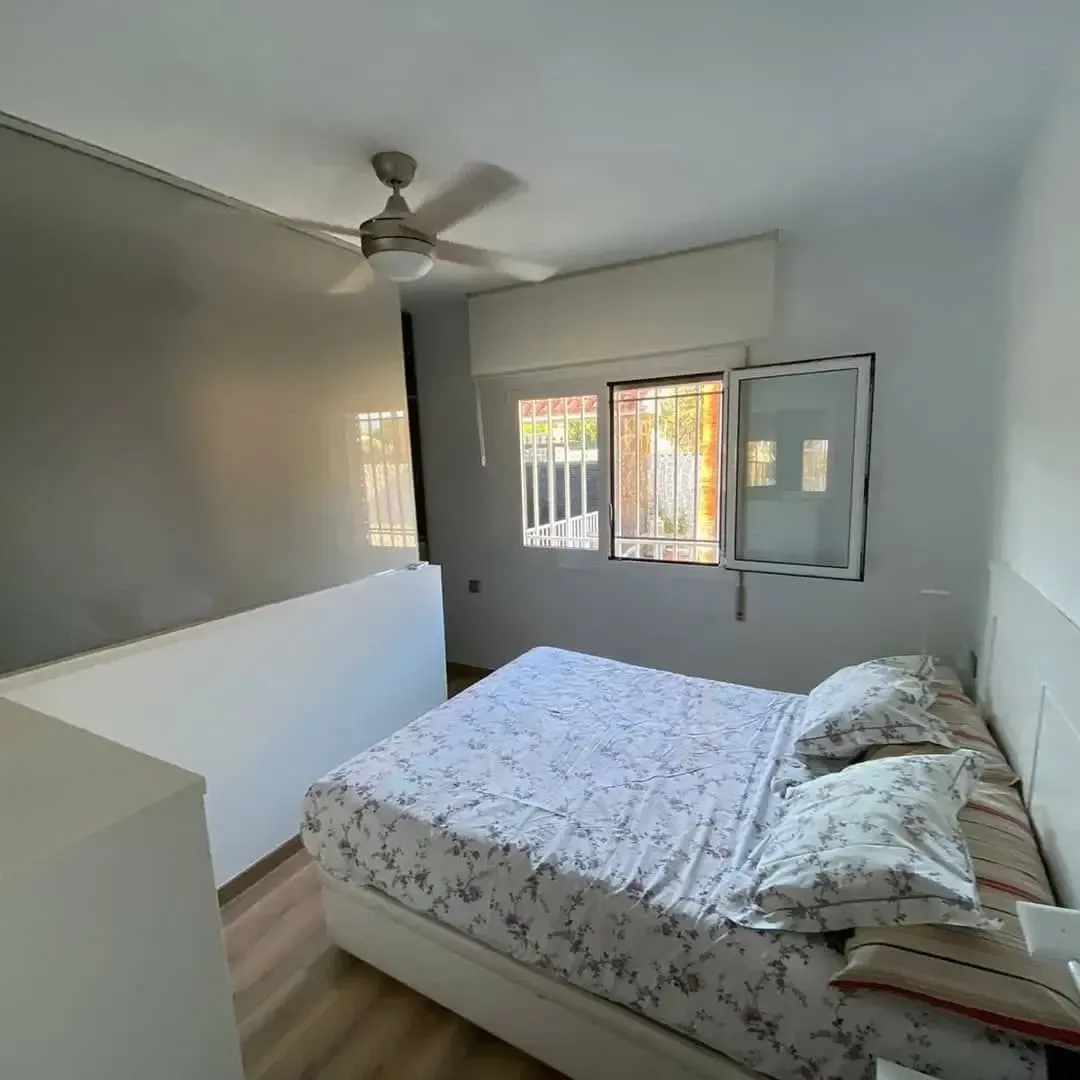 Un dormitorio con una cama y un ventilador de techo.