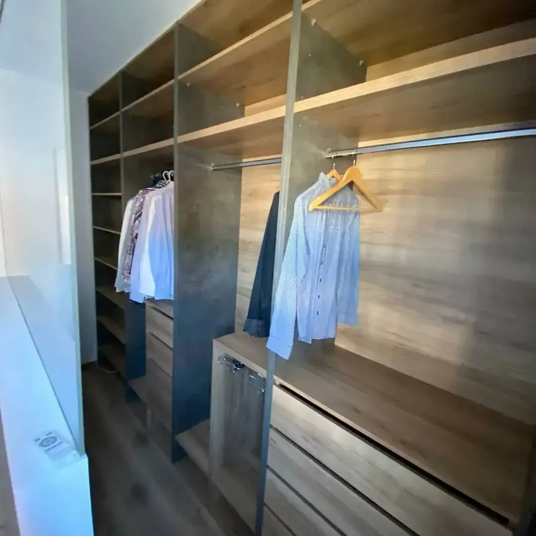 Un vestidor con ropa colgada en los estantes.