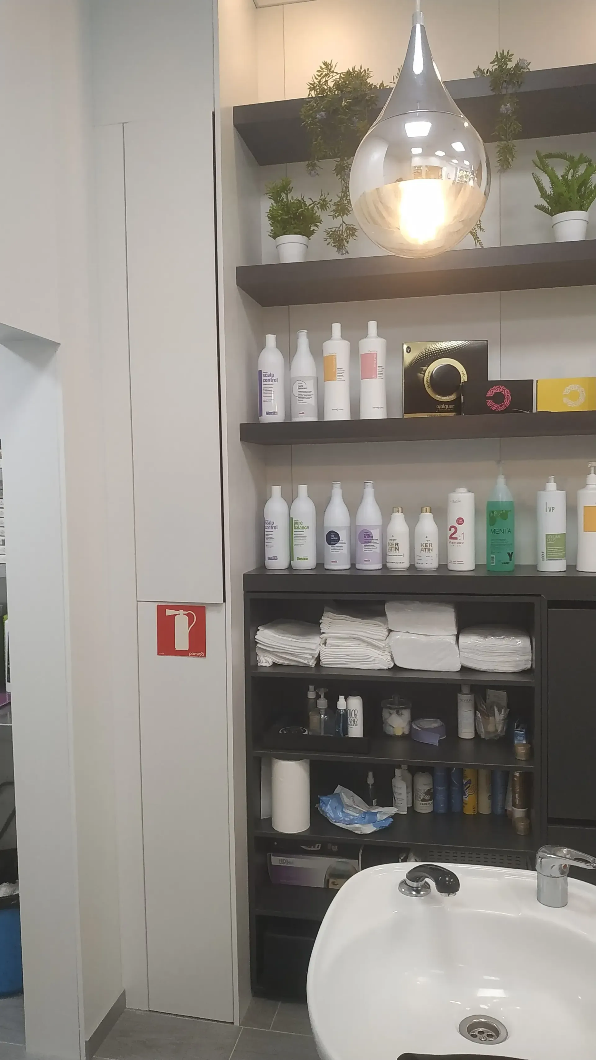 Un baño con un lavabo y estantes llenos de botellas de champú.