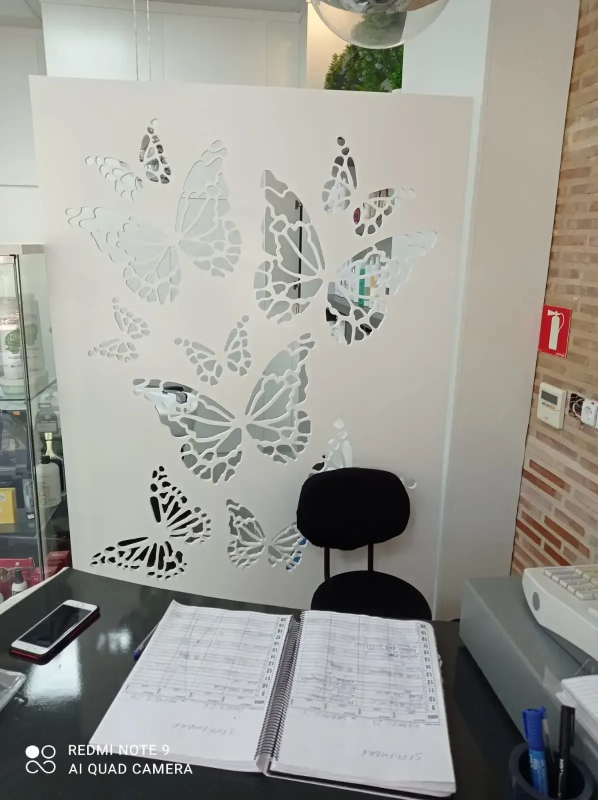 Un escritorio con un cuaderno y una silla frente a una pared con mariposas en ella.