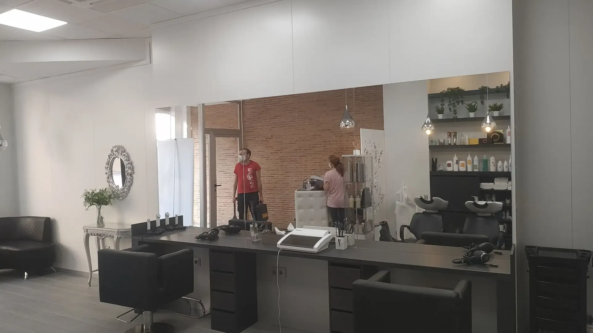 Un hombre con una camisa roja está de pie en una peluquería.