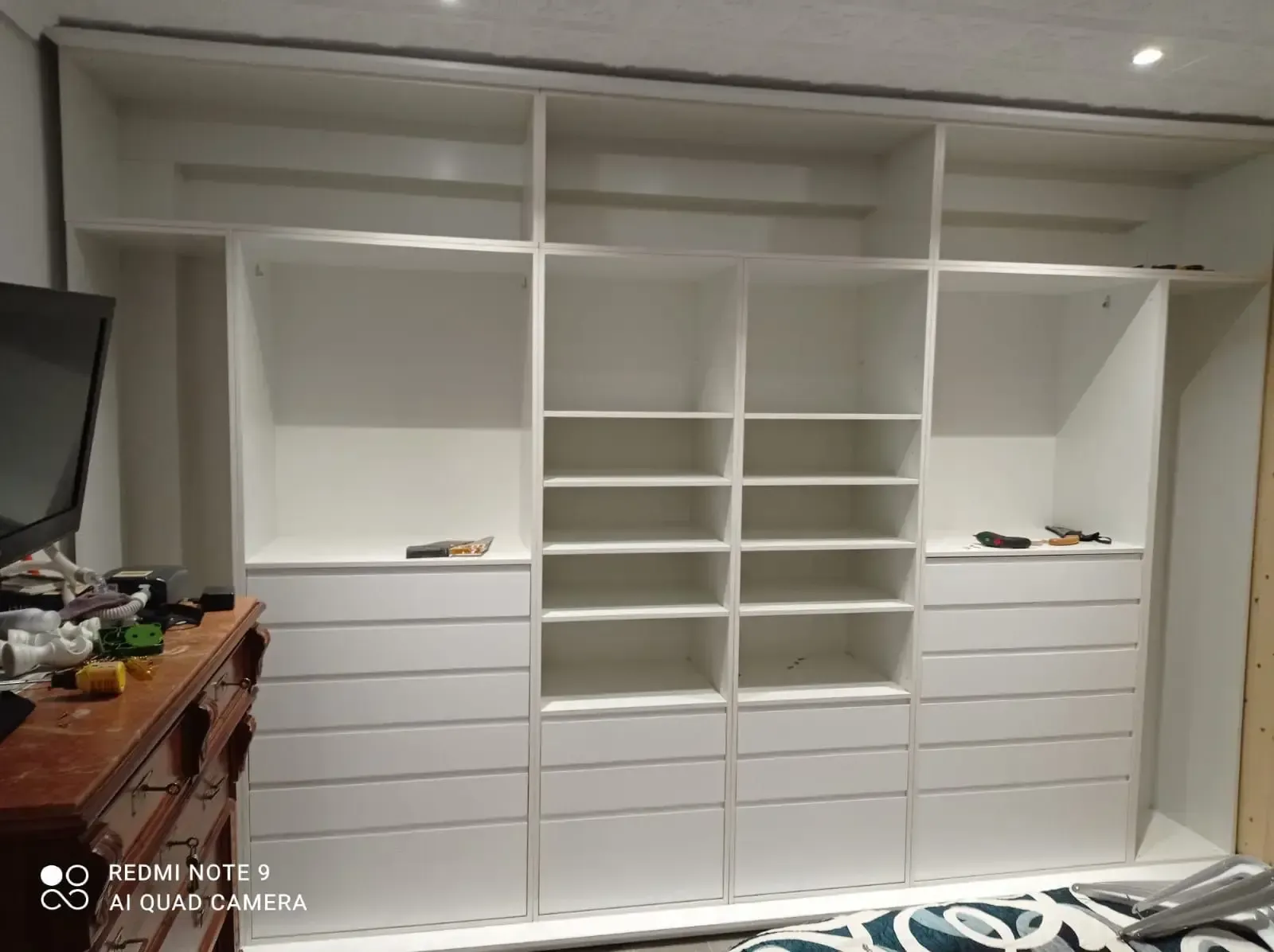 Un armario grande con muchos estantes y cajones en un dormitorio.