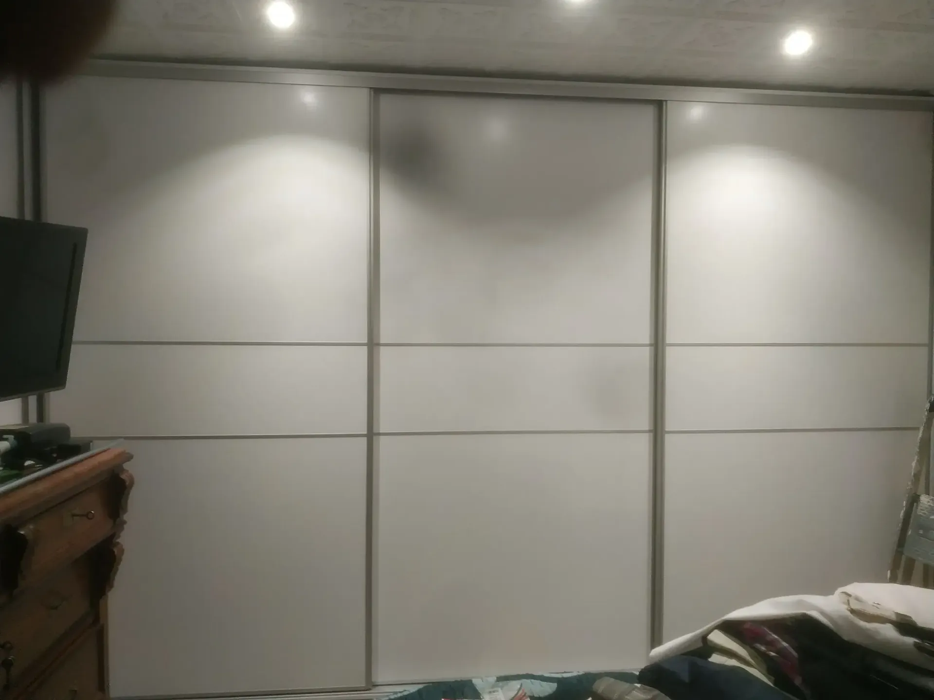 Un dormitorio con puertas correderas blancas y una cama.