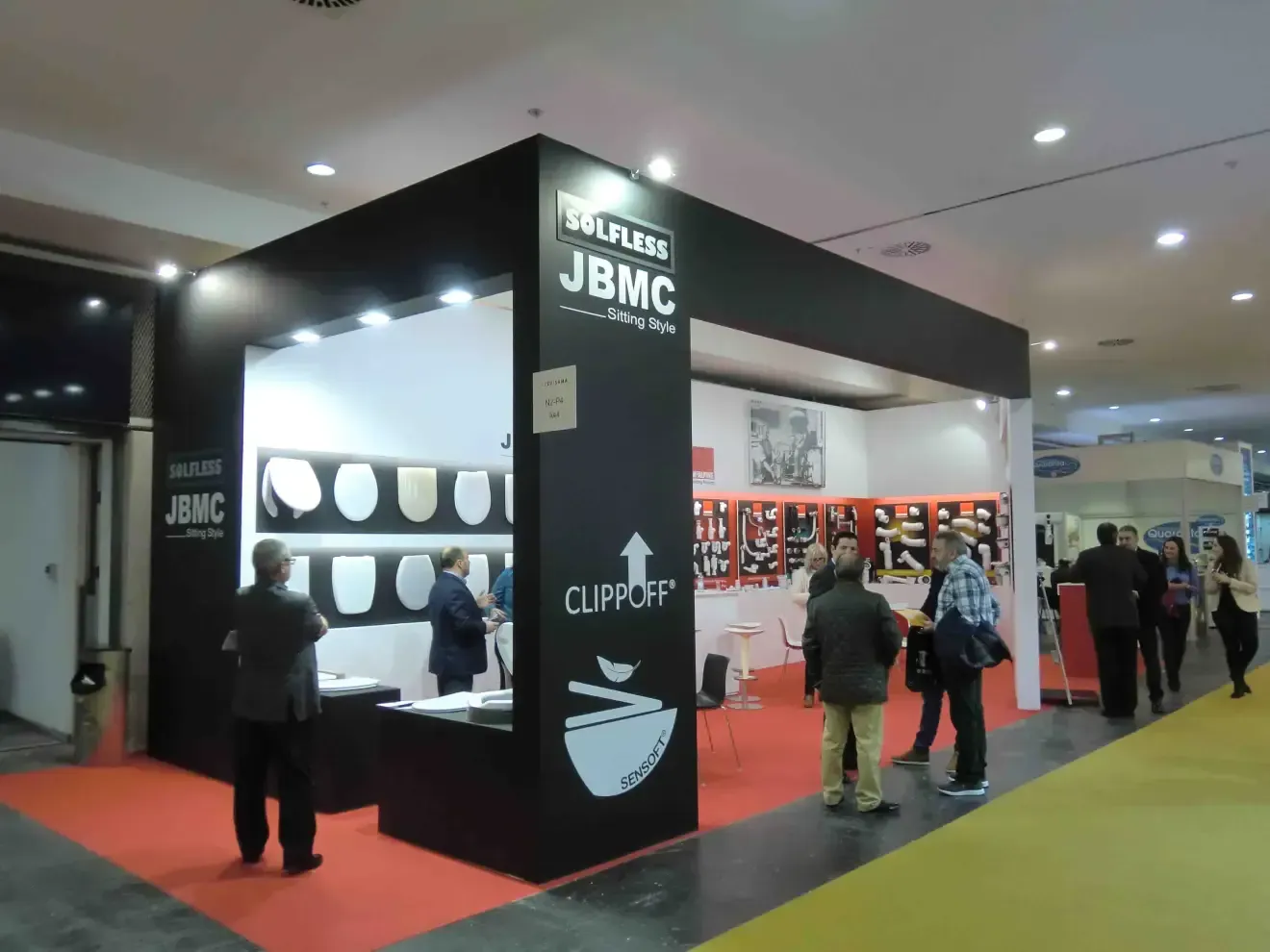 Un grupo de personas está de pie alrededor de un stand de JBMC.