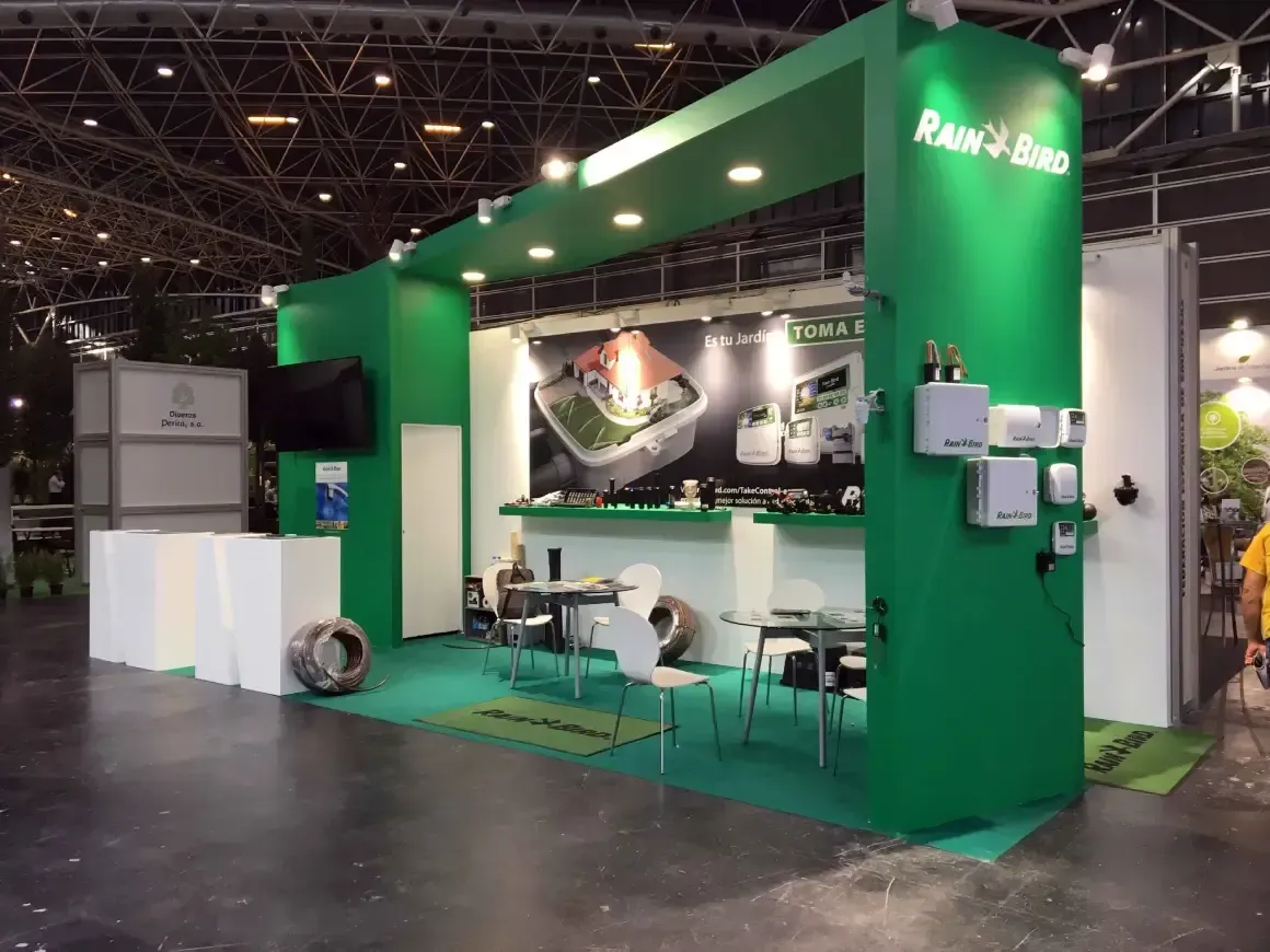 Un stand verde con mesas y sillas en una habitación.