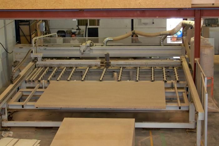 Una máquina está cortando un trozo de madera en un almacén.