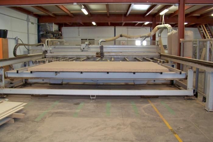 Una máquina está cortando un trozo de madera en un almacén.