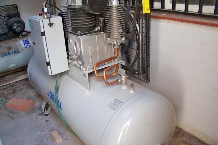 Un compresor de aire está en el suelo al lado de una pared.