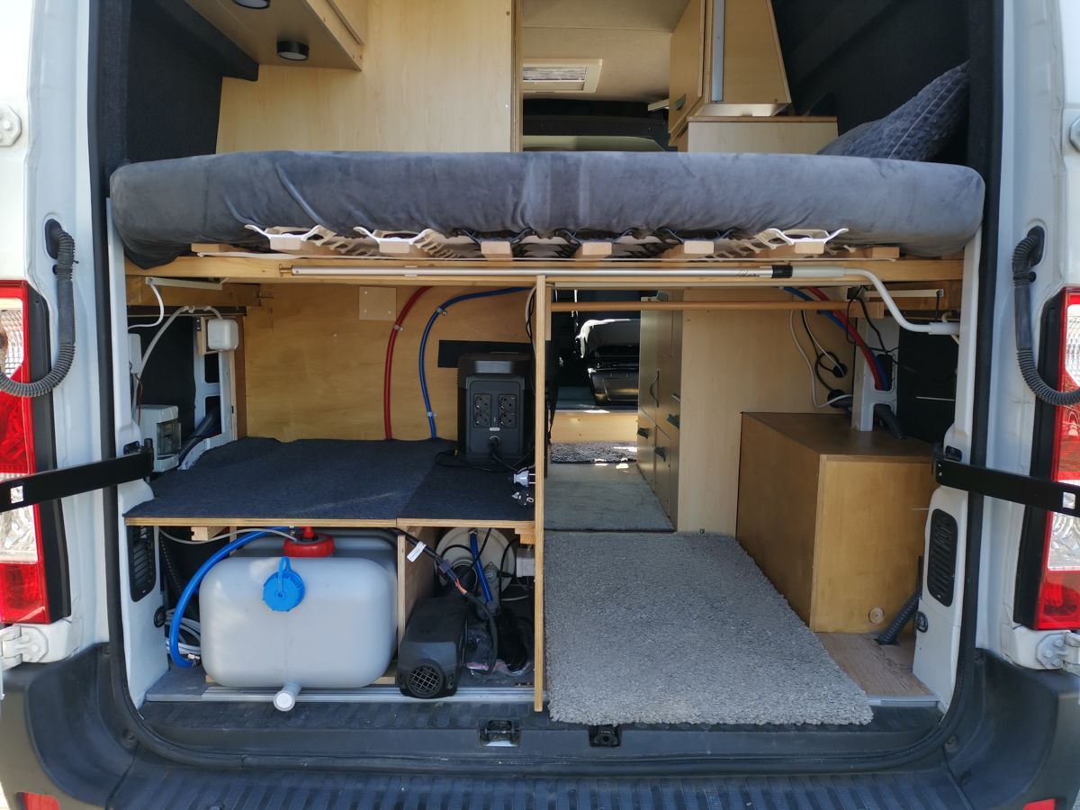 ein weißer Lieferwagen mit einem Bett und einem Wassertank