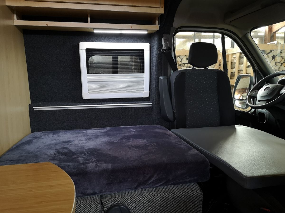 das Innere eines Lieferwagens mit einem Bett und einem Lenkrad