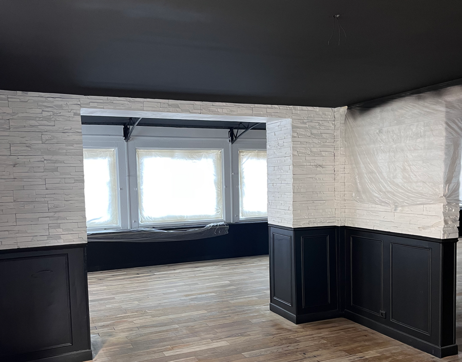 Pièce intérieure avec lambris noirs et murs en brique blanche.