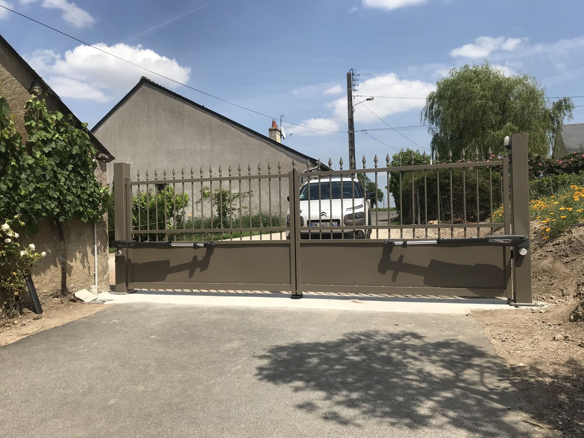 Voiture blanche souhaitant rentrer dans dans une propriété par le portail