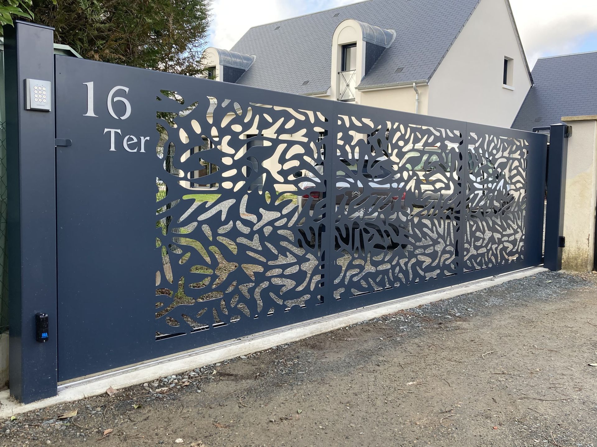 Portail gris bleu avec numéro 16 ter dessus et des motifs dessus