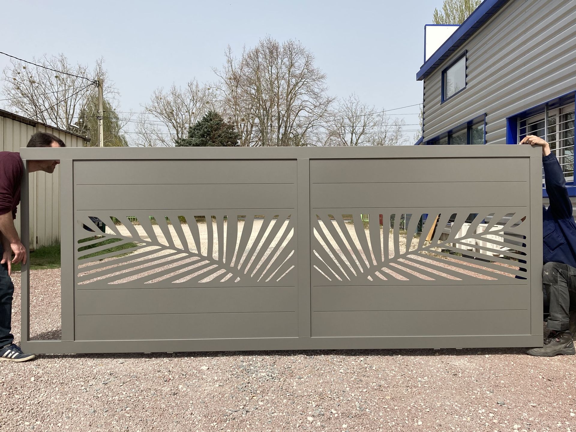 Portail vert avec forme de feuilles tenu par deux personnes