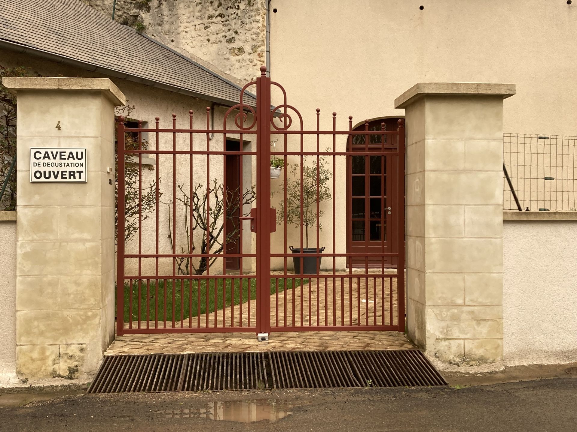Portail en ferraille marron avec un panneau sur le poteau d'à côté