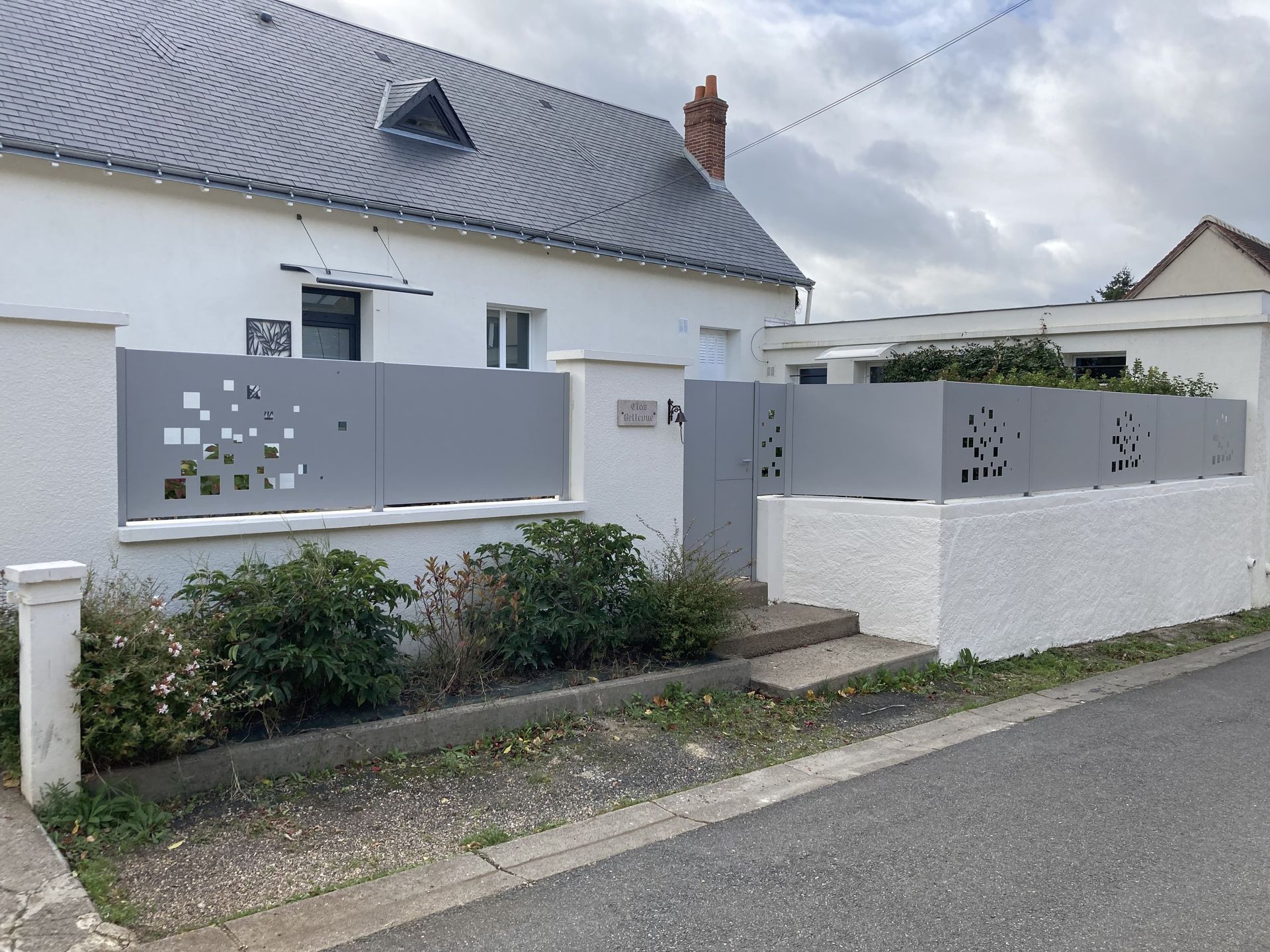 Clôture d'une maison en alu gris avec des trous carrés dedans