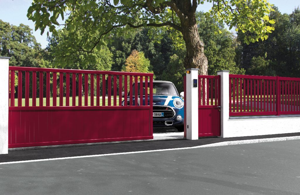 Voiture bleue derrière un portail coulissant rouge